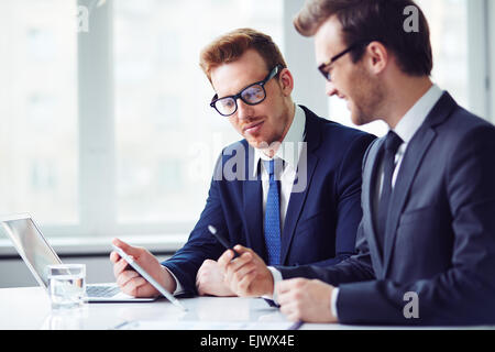 Young businessmen learning data upon new project at meeting Stock Photo
