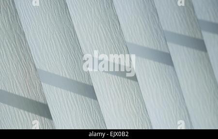 Vertical blinds with shadows from the sunlight. Stock Photo