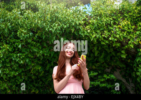 Woman using phone on green ivy background Stock Photo