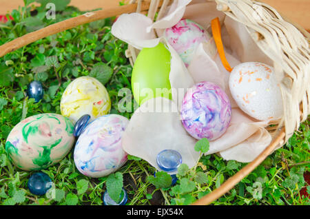 Basket full of hand colored Easter Eggs in decoupage placed on green grass surface Stock Photo