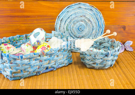 Blue basket full of hand colored Easter Eggs in decoupage shot against a wooden background Stock Photo