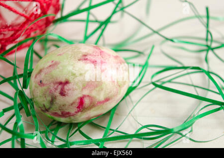 Hand painted  Easter egg on a table decorated with green straws Stock Photo