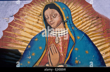 The peeling paint on a large mural of the Virgin of Guadalupe painted on the side of wall in El Paso,Texas. Stock Photo