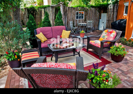 Holly Kinley has designed and made a  pretty backyard garden with an orange colored accent wall. Stock Photo