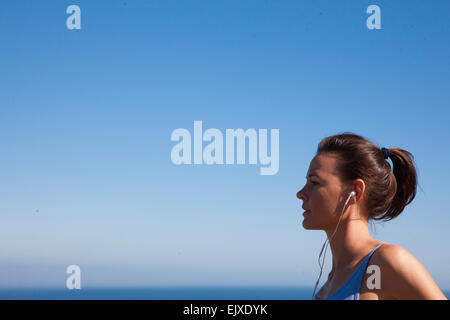 Profile of Woman Wearing Earbuds Running by Ocean