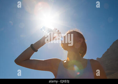 Woman Drinking Water from Bottle against Blue Sky