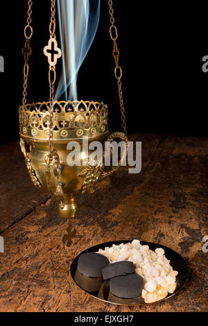 Smoking incense thurible and a golden plate with franincense and charcoal pieces Stock Photo