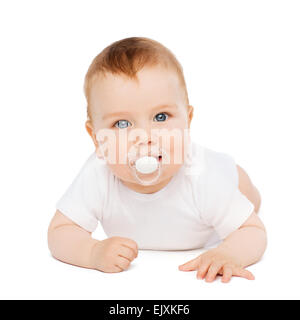 smiling baby lying on floor with dummy in mouth Stock Photo