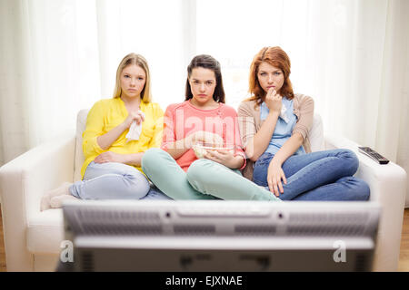 three sad teenage girl watching tv at home Stock Photo