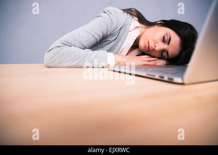 Young pretty woman sleeping on the table with laptop Stock Photo