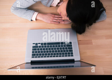Young woman sleeping on the wooden table with laptop Stock Photo