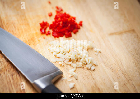 Chopped red chillies and garlic on a wooden chopping board Stock Photo