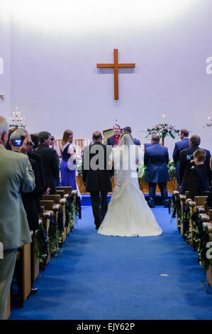 A bride is led down the aisle by her father at her wedding. Stock Photo