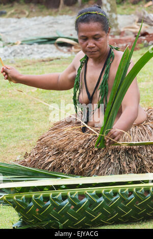 Yapese woman in traditional clothing weaving hand bag with palm tree leaves at Yap Day Festival, Yap Island, Federated States of Stock Photo