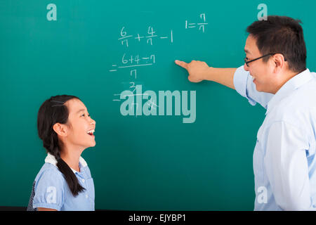 teacher with a little girl discussing  in classroom Stock Photo