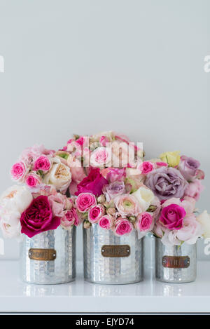 Bouquets of roses and ranunculus in tin containers in Paris apartment Stock Photo