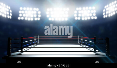 An boxing ring surrounded by ropes spotlit by floodlights in an arena setting at night Stock Photo