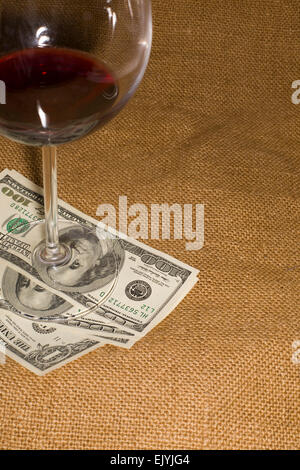 Glass of wine and a few US 100 dollars banknotes on the old tissue Stock Photo