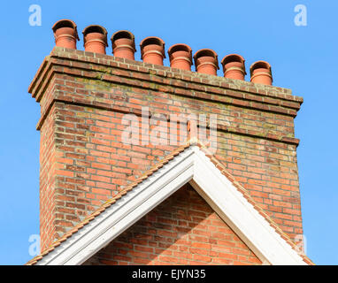 Chimney stack with 8 red chimney pots on a house in the UK. Stock Photo
