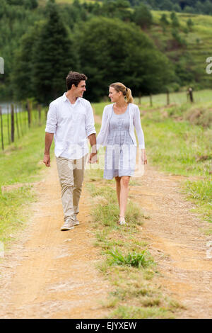 happy couple holding hands walking in countryside Stock Photo
