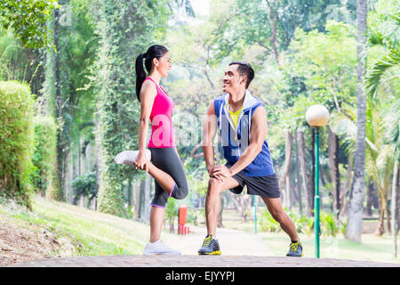 Asian woman and man, a couple, during gymnastics stretching for sport fitness in tropical park Stock Photo