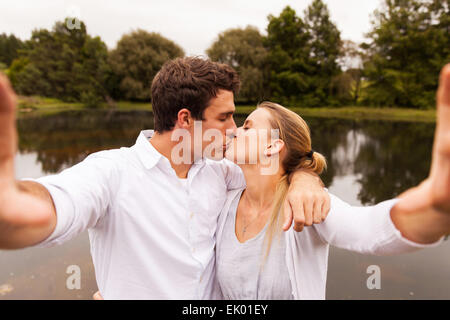 lovely young couple taking selfie kissing by the lake Stock Photo