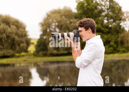 young man taking photos outdoors with camera Stock Photo