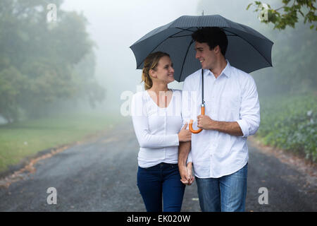 beautiful couple walking under umbrella in forest Stock Photo
