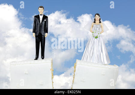 Bride and groom on split wedding cake with sky background. Stock Photo