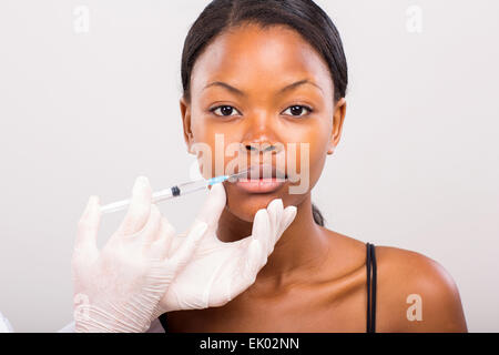 pretty young African woman receiving cosmetic injection in lips Stock Photo