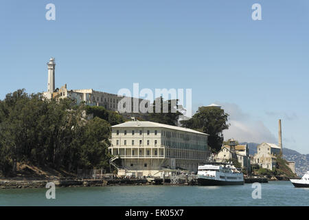 Blue sky view ferry docked  Building 64, below Lighthouse and Main Cell Block, south=east side Alcatraz, from San Francisco Bay Stock Photo