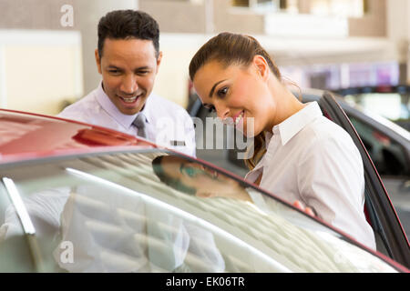 friendly middle aged vehicle dealer showing young woman new car Stock Photo