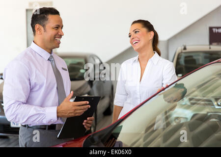 middle aged car salesman talking to a customer in showroom Stock Photo