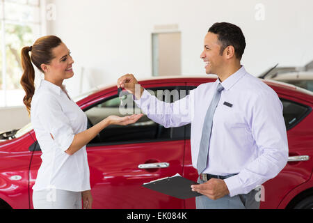 pretty young woman receiving car key from dealership Stock Photo