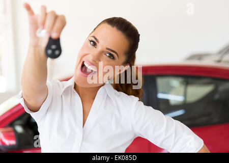 excited woman holding new car key at vehicle dealership Stock Photo