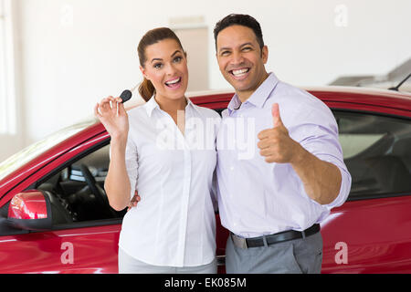 cheerful middle aged couple showing their new car key at dealership Stock Photo