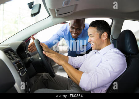 friendly African salesman explaining car features to customer Stock Photo