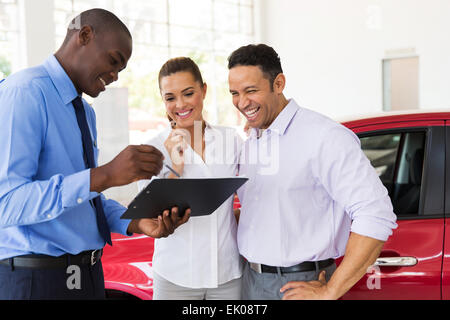 African car dealer explaining sales contract to couple buying a car Stock Photo