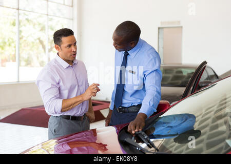 middle aged man talking to African car salesman inside showroom Stock Photo