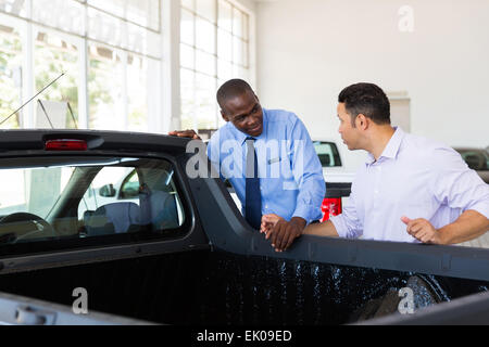 confident car salesman selling a car to middle aged customer Stock Photo