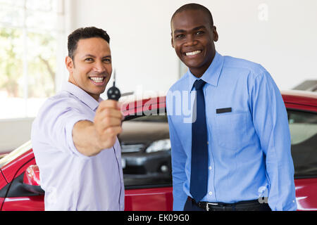mid age man showing new car key at dealership Stock Photo