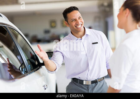 friendly salesman selling car to a customer in showroom Stock Photo