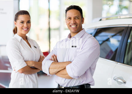 cute vehicle sales staff with arms crossed in car showroom Stock Photo