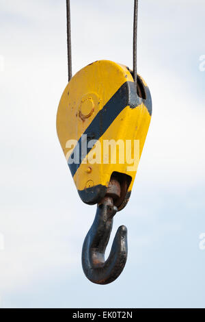 Crane hook hanging on steel ropes over cloudy sky background Stock Photo