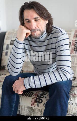 sad man sitting on a sofa in the room Stock Photo