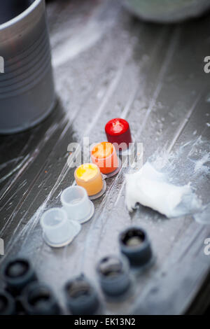 Colourful tattoo ink in small cups ready for being used on a tattoo, shot in a tattoo parlor Stock Photo