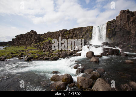 Waterfall flows over a cliff of lava rock formations in Thingvellir National Park Iceland Stock Photo