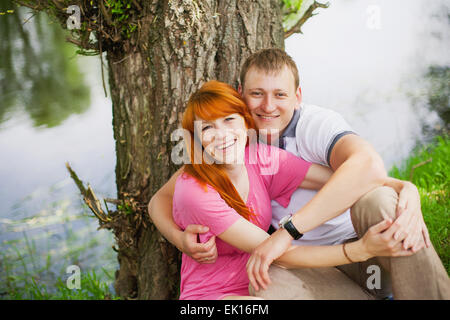 beautiful couple in love having fun outdoors, sitting on the bank of the lake, river Stock Photo
