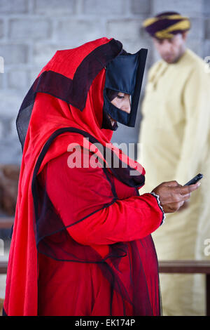 Bedu (Bedouin) woman with cell phone at animal market in Sinaw, Oman Stock Photo