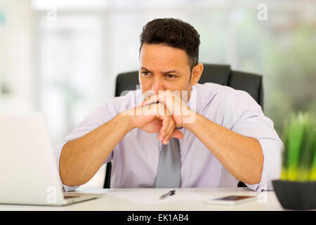 thoughtful middle aged businessman sitting in modern office Stock Photo